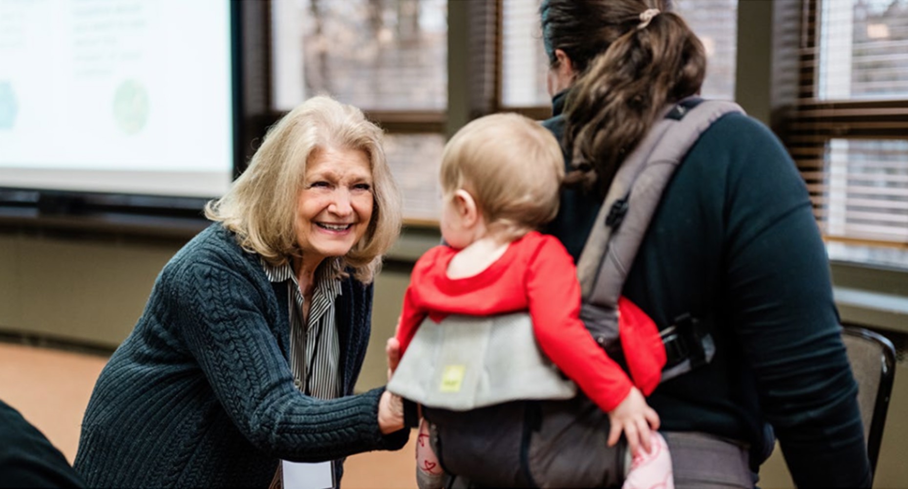 an older woman greeting a mother and her young child